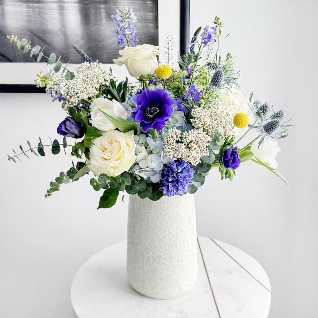 Bouquet of flowers in a white vase on a light surface with a neutral background