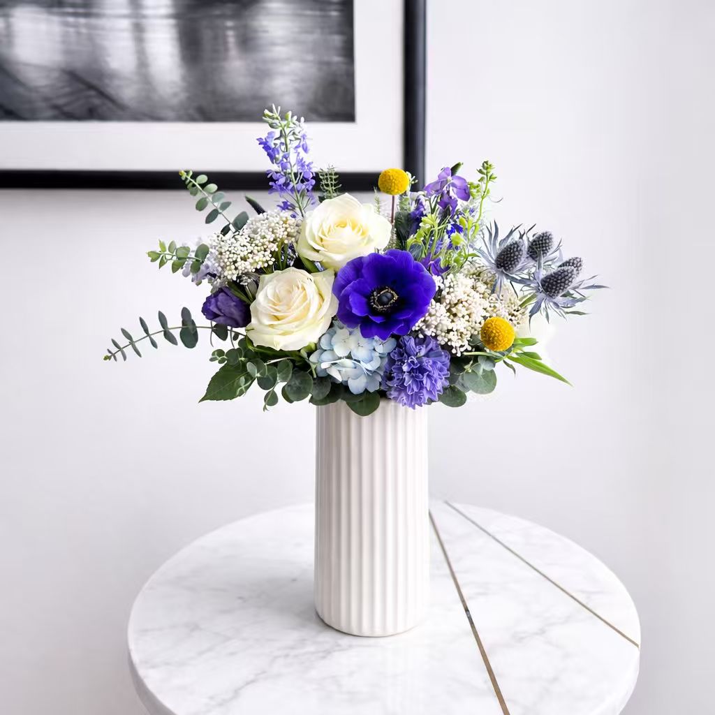 Floral arrangement in a white vase on a marble surface with a light gray background